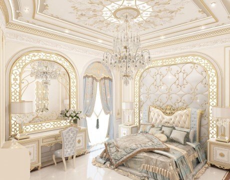 The picture shows a luxurious bedroom interior featuring white walls accented by an ornate gold chandelier and golden sconces. On the wall is an opulent oil painting in an ornate gold frame. The room also contains an upholstered headboard with a large bed dressed with a white and gold bedspread, and several coordinating cushions. To the right of the bed is a dressing table set upon a plush white and gold carpet, while next to it is a grand tufted ottoman. A wooden sideboard stands behind the ottoman with several v