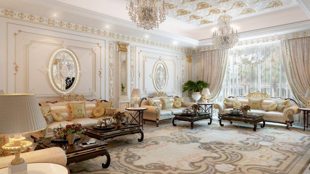 This picture shows an ornate modern bathroom suite. It features a light marble tile throughout the walls and floors, and gold accents on the fixtures. There is a two-person freestanding soaking tub, a separate wall-mounted rain shower, a double sink vanity with marble countertop and dual faucets, an enclosed toilet with a light fixture above it, and several wall-mounted shelves for storage.