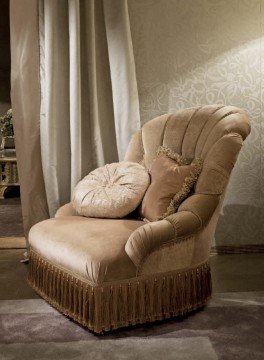 This picture shows a modern and luxurious living area, featuring an intricately carved marble wall with dark leather seating, complemented by an ornate gold circular chandelier, and decorative accents of wooden furniture, carpeted flooring, and potted plants. The entire space is lit with natural light from the large glass windows, giving it a bright and airy atmosphere.