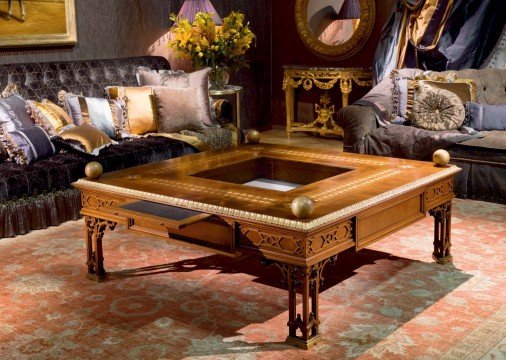 This picture shows a modern living room with a luxurious decor. The walls are white and there is a large grey sectional sofa, a round glass-top coffee table, a white and gold armchair, and a white fur rug. The floor is wood parquet, and there are several ornate lamps and light fixtures adding a warm glow to the room. The walls have artwork, plants, and various other decorative items.