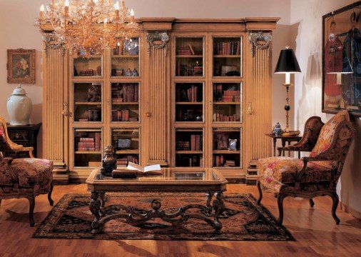 This picture shows a luxurious dining room with white marble floors, dark wood accents, and golden accents. The room features an elegant dining table with seating for four people, two low-hanging chandeliers, and two large windows with light drapery. On the walls are various pieces of art, including a painting of a woman in a pink dress, a black and white photo, and an abstract piece of art. Behind the table is an ornate armchair and a plush rug.