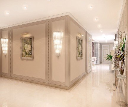 This picture is showing the interior of a luxury living room. The room is large and has modern furnishings and finishes. There is a white leather sectional sofa, two patterned armchairs, a glass coffee table, and a rug in the center of the room. The walls are painted a pale yellow color and there are large windows that allow for natural light to come in. A staircase is visible on the left side of the room and a doorway is seen on the right.