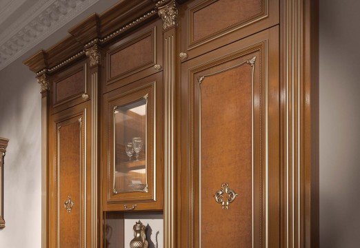 This picture shows a luxurious interior design. It features a combination of black and white furniture, with large windows that provide natural light. On the white walls are hung several ornate gold mirrors, while a white and gold mantel serves as the centerpiece of the room. On the floor is a shaggy black carpet. To the side is a bar cabinet which has two wall-mounted bottles of liquor. Finally, a large modern art painting hangs on the wall above the mantel.