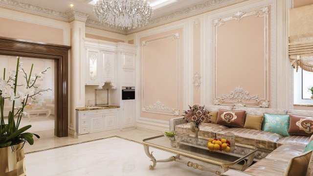 This picture is of a luxurious living room. The room features neutral-colored walls, a large cream-colored sectional sofa with accent pillows, an ornately carved wooden coffee table, and a beautiful chandelier hanging from the ceiling. There are two dark wood armchairs situated by an ornate fireplace, and a built-in bookshelf behind them. The room is decorated with artwork and accessories, including decorative vases and plants.