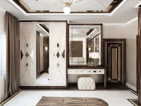 This picture is showing an elegant and luxurious bedroom. This bedroom features a rich, dark wood bed with a velvet headboard, flanked by two mirrored nightstands. The room has an upholstered armchair and ottoman in the corner, and a large framed mirror on the wall above. The walls are done in a light beige color with white crown molding and dark wood baseboards. A crystal chandelier hanging from the ceiling is the perfect finishing touch to complete this chic and sophisticated look.