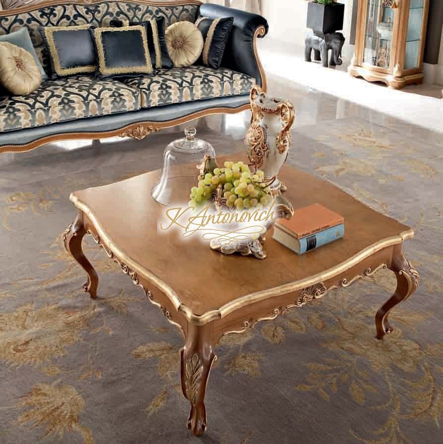 This picture shows a luxurious living room in an opulent home. The room features dark wood furniture, a plush rug, and large windows allowing lots of natural light. There are several art pieces on the walls, as well as recessed lighting providing a warm ambiance. In the center of the room, two cream-colored armchairs and a coffee table are arranged in front of a large fireplace with a decorative mantel.