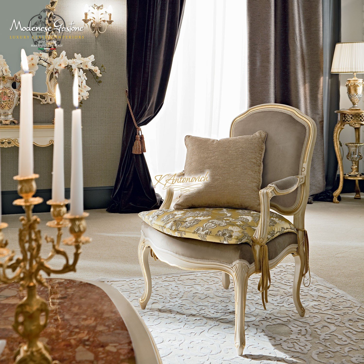 This picture shows a modern living room with an ornate and luxurious design. The walls are covered in an off-white silk wallpaper, with lighter accents along the upper corners of the room. The floors are a dark parquet wood and the centerpiece of the room is a grand piano in the center of the room. The furniture is all in white and accented by velvet and glass tables, and a luxurious rug to complete the look. The walls are decorated with art and the large windows have curtains that are adorned with classic gold finishes.