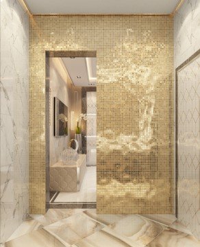 This picture shows an ornate, spacious bathroom with a deep soaking tub in the center. The walls are light gray, and the floor is tiled with dark-colored marble. The tub is surrounded by two windows that are framed with thick, white curtains. There is also a corner shower stall with a large frameless glass door, as well as a long white sink counter with two sinks and two wall-mounted mirrors. The room is adorned with chandeliers, framed artwork, and ornate details such as crown molding and marble accents.