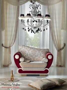 A contemporary living room featuring a distinctive, curved white sofa upholstered in gray velvet and an abstract art piece.