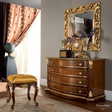 This picture shows a luxurious and modern living room. The room is decorated with white walls and light wood flooring, and features a large brown leather sofa and two matching arm chairs. There is a modern glass-topped coffee table in the center of the room, along with a pair of black side tables and a large beige area rug. The walls are adorned with a pair of abstract art pieces and a mirror, and there is a large potted plant in the corner completing the look.