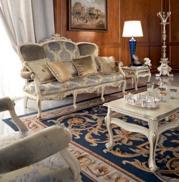 This picture shows a luxury modern living room with a dramatic black and white color scheme. The room features a white marble floor, modern sofas and upholstered chairs in black, white and gray, glass coffee tables, and a luxurious crystal chandelier. The walls are adorned with black and white framed artwork, and the back wall is decorated with a light gray and black striped wallpaper.