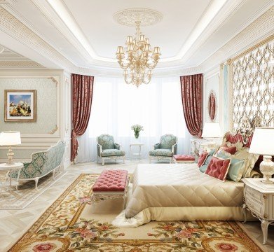 The picture shows an elegant living room within a luxury home. The space features a sleek gray sofa and two matching armchairs. A colorful area rug lies atop the white marble floor, and a gold-framed round mirror hangs above an ornate decorative fireplace. Pristine white walls and tall windows fill the room with natural light, while a glass top coffee table and a collection of matching accent pillows complete the stylish decor.