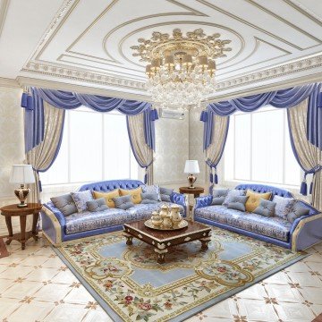 This picture shows a luxurious living room with a contemporary design. The room has a light blue velvet sofa and matching armchairs, as well as modern art on the walls. The room also features an ornate chandelier hanging from the ceiling, an area rug with a geometric pattern, and a glass-top coffee table with a chrome base.