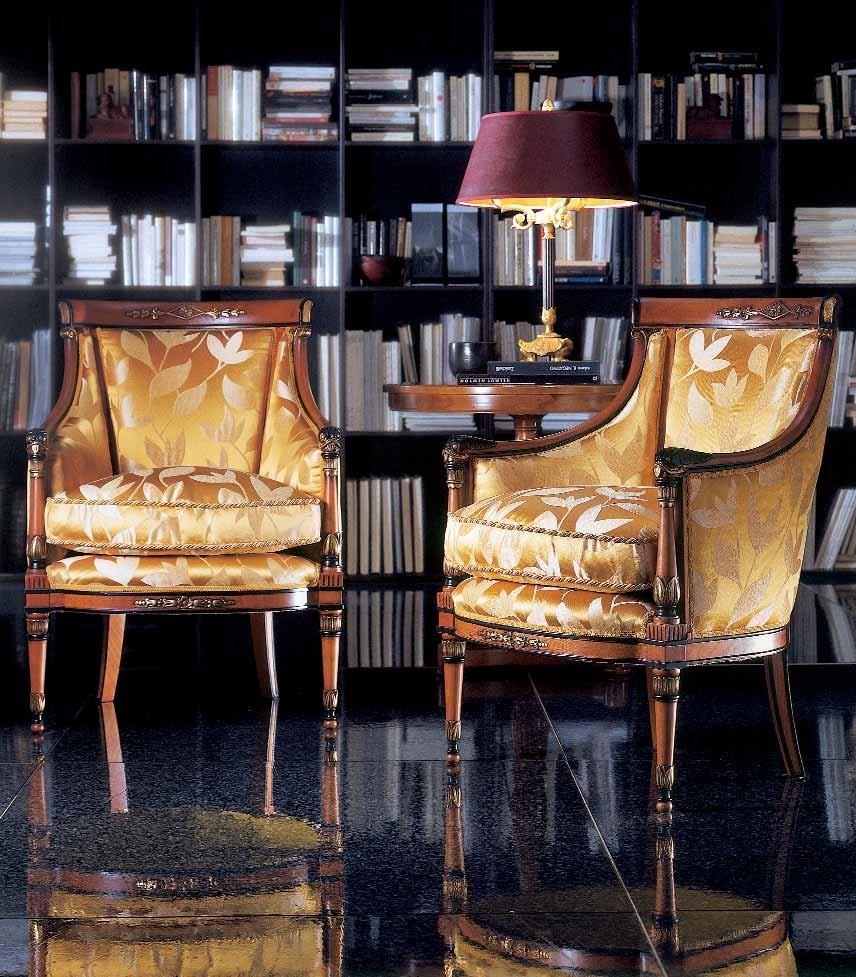 This picture shows a modern living room that has been elegantly decorated. The walls are a light beige color, and the floor is a dark hardwood. There is a large sofa with a few armchairs in the center of the room, and a unique circular coffee table in front of them. On the wall behind the sofa is a decorative mirror with a golden frame and a white marble mantle underneath. Two tall windows with sheer white curtains frame the seating area, and a white ceiling fan hangs above. The room is balanced with a beautiful ceramic vase next to the fireplace, and a