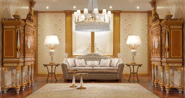 This picture is a close-up of a modern interior featuring an elegant and contemporary black and white marble floor with a border of mosaic tiles and a white leather sofa with two matching armchairs. The walls are painted in a soft off-white color, and the room is illuminated by a beautiful ornamental chandelier.