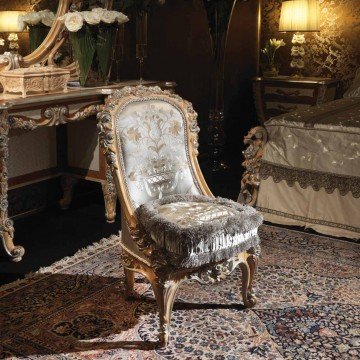 This is a picture of a modern luxury dining room. The room features exquisite black and white marble floors, luxurious white curtains, and walls lined with gold and black wallpaper. A large wooden dining table is in the center of the room and is surrounded by striped chairs upholstered in rich gold velvet. Several high-end light fixtures are hung around the room to provide extra lighting.