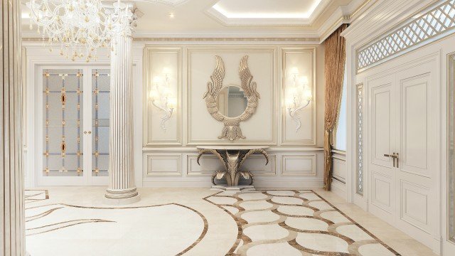 This picture shows an ornate, modern-style bathroom with a white vanity, gold-colored accents and a light gray tile floor. The vanity has a large, rectangular white sink basin with two golden fixtures, a white stone countertop, and two soft-closing drawers. Behind the sink is a large, framed mirror with two elegant golden wall sconces. The room features light gray tiled floors and walls with white trim and molding. On the left side of the bathroom is a large jacuzzi-style bathtub with a textured stone wall behind it