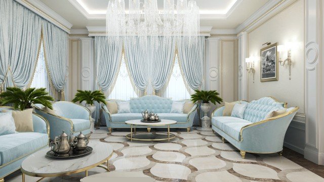 This picture shows an elegant modern living room. The room features several luxurious pieces of furniture, including two white couches with gold trim and a deep purple velvet armchair. There is also a large round coffee table with a glass top, a large decorative mirror on the wall, and a black marble fireplace. The walls are painted in a light gray color with silver accents and the floor is covered with a dark plush carpet.