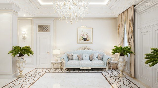This image appears to show a grand, opulent living room in a luxurious home. The walls are covered in an ornate white wallpaper with gold and black accents. There is a large white sofa with cream, tufted cushions, along with two matching armchairs. An ivory-colored rug with gold and black patterns lies on the floor beneath the furniture. On the wall to the left is an abstract painting with deep blues, greens, and yellows. To the right of the sofa is a white grand piano with a glossy black lid. The room is illuminated by a grand,