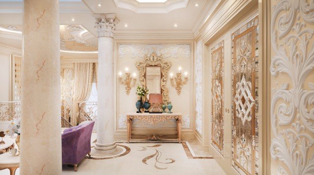This picture shows an ornately decorated bathroom with marble flooring, walls, and countertops. On the wall behind the double vanity sink is a large mirror framed in gold and highlighted by sconces on either side. The vanity has two sinks, with gold fixtures and a stone backsplash. There is also a Jacuzzi bathtub with gold accents and a rainfall showerhead. The walls are covered in a beige wallpaper with gold accents and a small chandelier hangs from the ceiling.