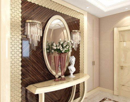 This picture shows a luxurious living room with a regal design. There are rich brown hardwood floors, beige walls, and modern white furniture with gold accents. A bold center table is surrounded by two neutral-colored sofas and a velvet armchair. An ornate white and gold chandelier hangs from the ceiling and an elegantly framed portrait is suspended on the wall. The overall atmosphere of the space is cozy and inviting.