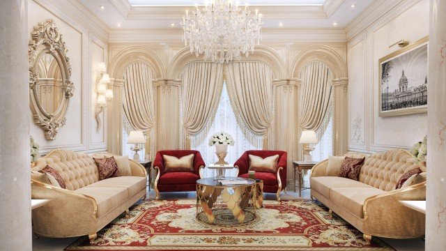 This picture shows a luxurious living room with a white marble floor, deep red leather couches, and a modern chandelier. A large decorative stone wall is the backdrop for two armchairs, while a long beveled mirror is mounted above the fireplace. The center table appears to be made of glossy black lacquer, and it is surrounded by several small accent tables and a colorful abstract painting.