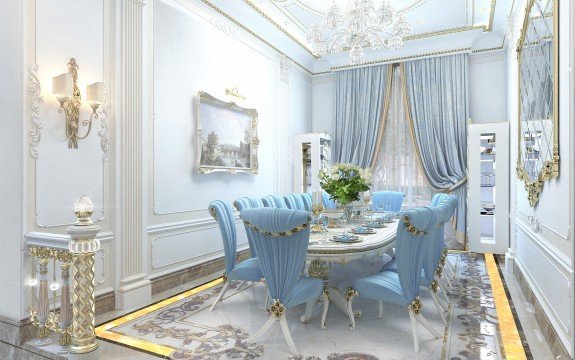 This picture shows a white and gold living room with a lavish interior design. The walls are a buttery cream color and the ceiling is painted in a glossy gold color. In the foreground of the picture, there is a large white sofa with four throw pillows and two gold-colored armchairs. In the center of the room is a gold-framed mirror that reflects the rest of the space. On the right side of the room, there is a wooden end table with a golden trumpet decor piece sitting on top of it. The floor is made up of light-colored tiles.