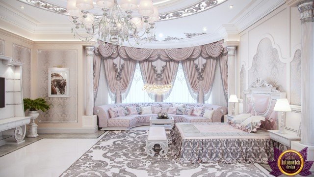 This picture is of a modern, luxury living room. It features a grey sofa, two white armchairs, and a black stone coffee table in the center of the room. The walls are painted soft white and decorated with a large abstract painting. There is a silver and glass chandelier suspended from the ceiling, adding to the opulent décor. A metallic grey rug contributes to the chic yet inviting atmosphere of the space.