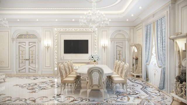 This picture shows a luxurious interior design with a seating area featuring comfortable-looking white upholstered chairs and a pink velvet sofa in the center. The walls are adorned with large patterned wallpapers and framed artwork. A black marble fireplace is visible on the right wall with a silver mirror on top of it. There are also two decorative lamps on either side of the fireplace, adding to the elegant atmosphere of the room.