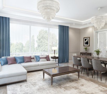 This picture shows a modern bedroom space with a bold, contemporary design. The room features an upholstered bed centered along one wall with a curved headboard and tufted detailing. The bed is dressed with a plush gray bedspread and large, white pillows. On the side wall is a gray velvet sofa, and a round, glass-topped coffee table sits in the center of the room. The walls are painted in a dark navy hue and the floor is finished with a light hardwood. Large windows provide plenty of natural light, and several pieces of art decorate