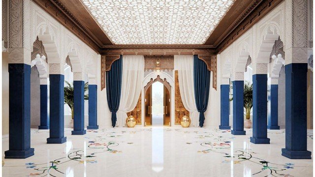 This picture shows a grand luxury hallway in a home. It features a marble floor with intricate patterns and accents, a crystal chandelier hanging from the ceiling, and arched doorways leading to different rooms. There are luxurious furnishings and decor, displaying an opulent and sophisticated aesthetic. The walls are adorned with ornate moldings and artworks, giving the hallway an elegant and luxurious feel.