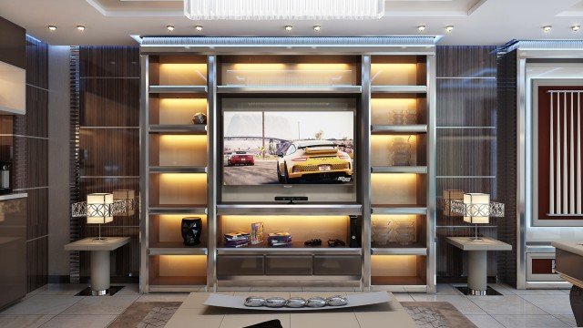 This is a picture of a modern, luxurious living room. The room features a white leather sectional, two decorative round poufs, and a high-gloss coffee table with a glass top. The walls are decorated with gold accents and framed artwork. The hardwood flooring is light-colored and the ceiling has recessed lighting. Large windows let in streams of natural light.