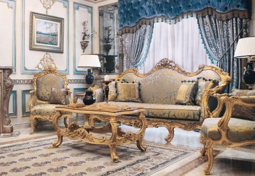 This picture shows a modern luxury dining room with a dark wood table and chairs surrounded by a white and gold-accented wall. The room is illuminated by a large chandelier overhead and two tall candelabras on either side of the table. The shades of the light fixtures provide warm lighting, while the wall color and golden accents add a touch of glamour and opulence. The table is set with dinnerware and elegant decor pieces, providing a pleasant and inviting atmosphere.