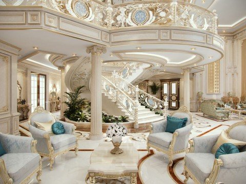 This picture shows a luxurious living room with a lavish and sophisticated interior design. The walls and floor are covered in elegant cream and white marble tiles, while the ceiling is embellished with an ornate gold chandelier. There is a window at one end of the room, and a large tan leather sofa with a matching armchair in the center. The furniture is further complimented by two stylish gilded side tables and a glass coffee table with decorative metal legs. In the background, a beautiful painting of a chateau hangs on the wall above a glossy black piano.