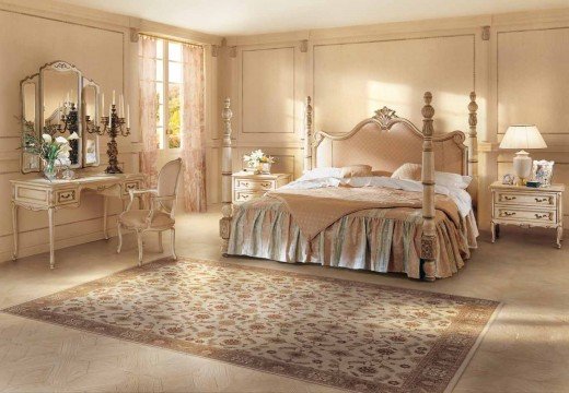 This picture shows a modern and stylish bedroom. The room is decorated in shades of white and light gray, with dark wood furniture. There is a large bed with white blankets and pillows, as well as a nightstand and dresser with drawers. A large mirror hangs on one wall, and there is a rug on the floor. The large windows provide plenty of natural light and a view of the city.