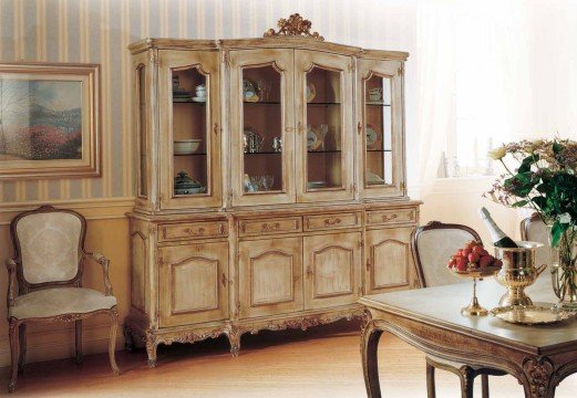 This picture shows a luxurious living room with a white marble floor and gold accents. The walls are covered in a navy blue velvet fabric, and the furniture is plush and inviting. There is a large, curved sofa in the center of the room, with two matching armchairs on either side. There are also two small side tables and a large gold-framed mirror on the right-hand wall.