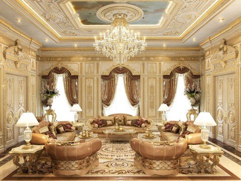 This picture shows an opulent, contemporary dining area with golden accents. The walls are a cream/ivory color and the ceiling is an ornate white design. The walls include hanging decor, such as large mirrors and framed art. The floor is a sleek, light wood. In the center of the room is a round marble dining table with a golden base and six cream chairs surrounding it. The chairs have intricate designs and luxurious fabric upholstery with golden accents. On the table is a large, golden candelabra with crystal pendants. Above this hangs a luxurious gold ch