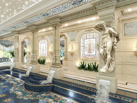 The picture shows a grand marble staircase with beautiful bronze and gold trims. The staircase is decorated with a large crystal chandelier, and there are several ornate pedestals with marble columns on either side. The stairs lead up to a landing featuring a luxurious brown and gold velvet sofa with a white marble table and two matching chairs.