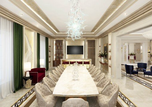 This picture shows a luxurious living room designed with a modern aesthetic in mind. The room has a white marble floor, a large white leather tufted sectional sofa, an ornate beige and gold chaise lounge, and multiple decorative accents. The focal point of the room is a crystal chandelier hanging from the high ceiling, and walls are covered with gold-trimmed beige wallpaper. On the left side of the room, two beige armchairs face each other in front of a fireplace. The right side of the room features a tall window looking out onto a