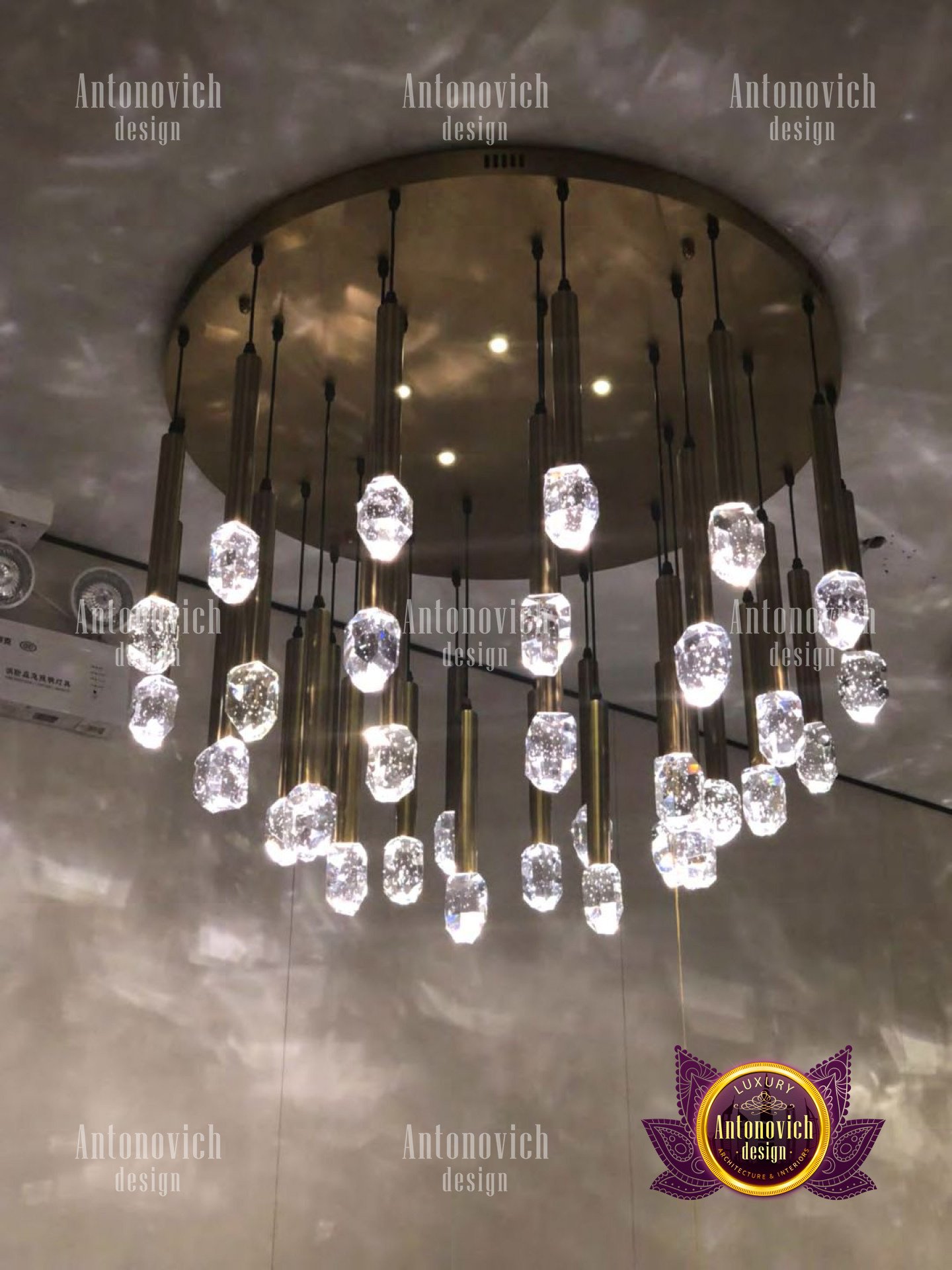 A high-end luxury living room featuring intricate gold detailing on walls and furniture, and a crystal chandelier.