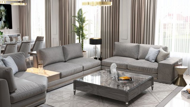 This picture shows a modern living room with high white walls, a large area rug, hardwood flooring, and multiple seating options. A white sectional sofa and light grey armchairs are situated to the left of the space, while a large chaise lounge is placed in the center of the room. A glass coffee table and two tall rattan poufs fill up the middle of the room. On the right side of the room, there is a white bookcase with multiple drawers for storage. Recessed lighting and two round wall sconces provide a subtle glow in the