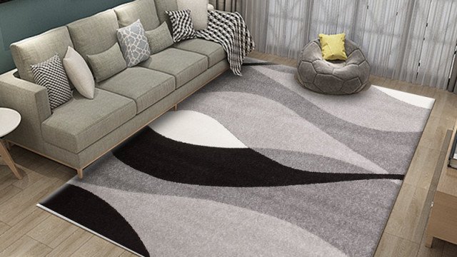 This picture shows an expansive, modern living room space with a curved white leather couch situated in the center. The walls are decorated in a light gray color and feature two large square pillars with gold border detail. The floor is tiled with beige marble and accented with a large white rug underneath the couch. The room also has several contemporary lamps for added lighting.