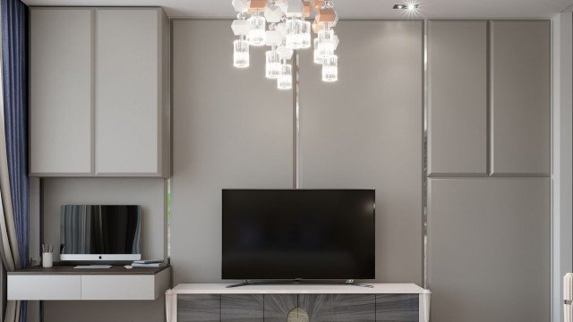 This picture shows a luxurious modern living room with a unique patterned crystal chandelier hanging from the ceiling. The color palette includes shades of white and beige for the walls, furniture, and carpeting, with accents of grey, black, and gold throughout. There is a comfortable sofa sitting in the center of the room, along with multiple armchairs and a plush ottoman. Artwork hangs on the wall and a grand piano sits to the side.