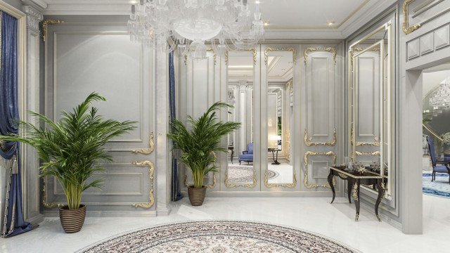 This picture shows a luxurious formal dining room designed by Antonovich Design. The walls and ceiling are intricately decorated with floral patterns. The room is lit up by a large crystal chandelier, and surrounded by a number of elegant chairs upholstered in white fabric along with a grand grand piano at the corner. The warm wooden floor gives the room a cozy ambiance along with the red velvet curtains at the sides.