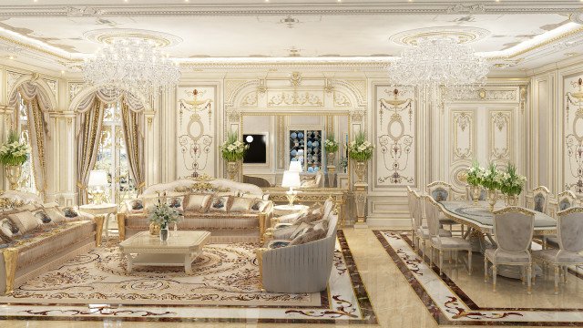 This picture shows a luxurious bedroom interior with a large bed with ornate bedding, a pair of matching armchairs and ottomans, a round side table and a matching dresser. The walls have an elegant beige hue and are adorned with a painted damask pattern, while the room is illuminated with various lighting fixtures.