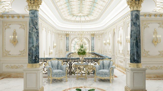 The picture shows a spacious marble entrance hall. The walls are adorned with detailed carvings and the floor is made of black and white marble tiles arranged in an intricate pattern. An elaborate chandelier hangs from the ceiling above a luxurious round sofa, while two grand staircases lead to the upper levels. There are also several large potted plants scattered around the room to add a touch of greenery.