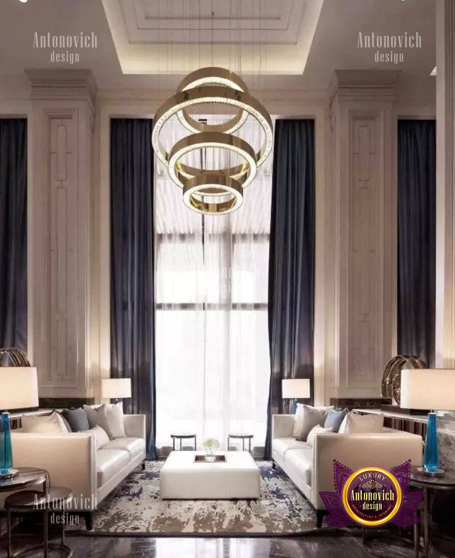 The picture shows an elegant master bedroom, featuring a traditional style and a neutral color palette. The room is decorated with an oak wood headboard, a white linen upholstered bed, an antique side table, and a pair of crystal chandeliers. The walls are painted in a light beige color and are adorned with two large landscape paintings. The flooring is a beige marble, and the window treatments are a unique combination of patterned golden curtains and sheer white drapes.