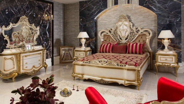 A luxurious room with white and gold decor, featuring a large chandelier, a sofa, and a coffee table near the window.