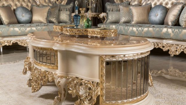 This picture shows a luxury bathroom designed by Antonovich Design. The room features a marble floor and walls, golden accents, and a spa-style soaking tub with shower. There is a large vanity with two sinks, a built-in storage cabinet, and golden-framed mirrors. The window has ornate decorations, and the ceiling has a decorative medallion with a chandelier.