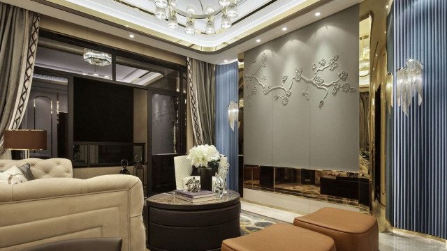 This is a picture of an ornately-decorated kitchen interior. The space has a classic and luxurious feel, with the dark wooden cabinets, marble countertop, and decorative accents. The unique backsplash tile pattern creates an eye-catching focal point on the wall, while the island provides ample storage and prep space. Gold and silver light fixtures hang from the ceiling, adding a touch of glamour to the design.